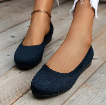 Navy blue flats worn on a wooden floor
