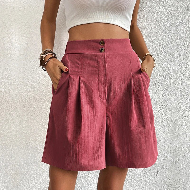 Person wearing a white crop top and pink shorts against a textured white wall.