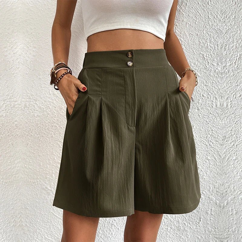 Person wearing a green skirt with a white top against a textured white wall.