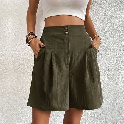 Person wearing a green skirt with a white top against a textured white wall.