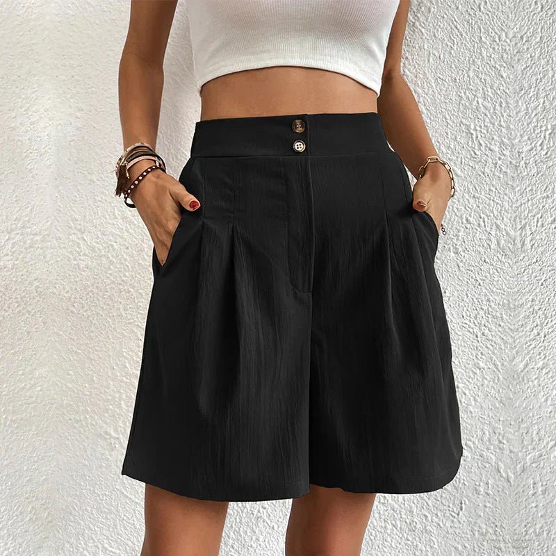 Person wearing a black skirt with a white top against a textured white wall.