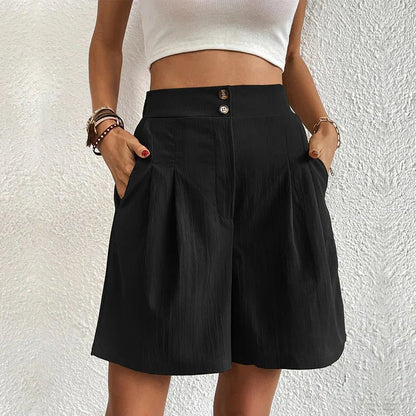 Person wearing a black skirt with a white top against a textured white wall.
