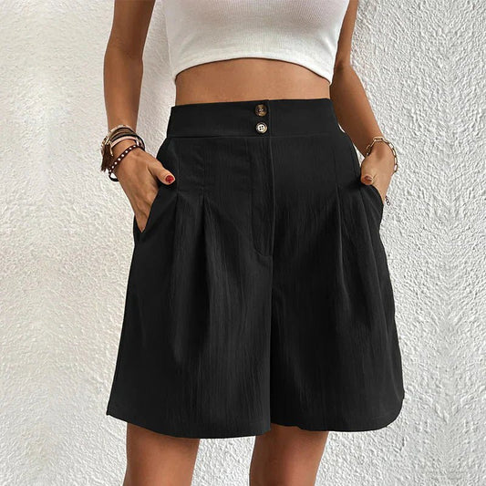 Person wearing a black skirt with a white top against a textured white wall.