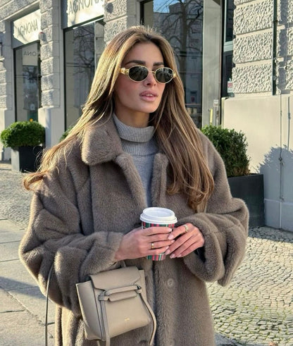 Woman in a brown coat holding a coffee cup outdoors