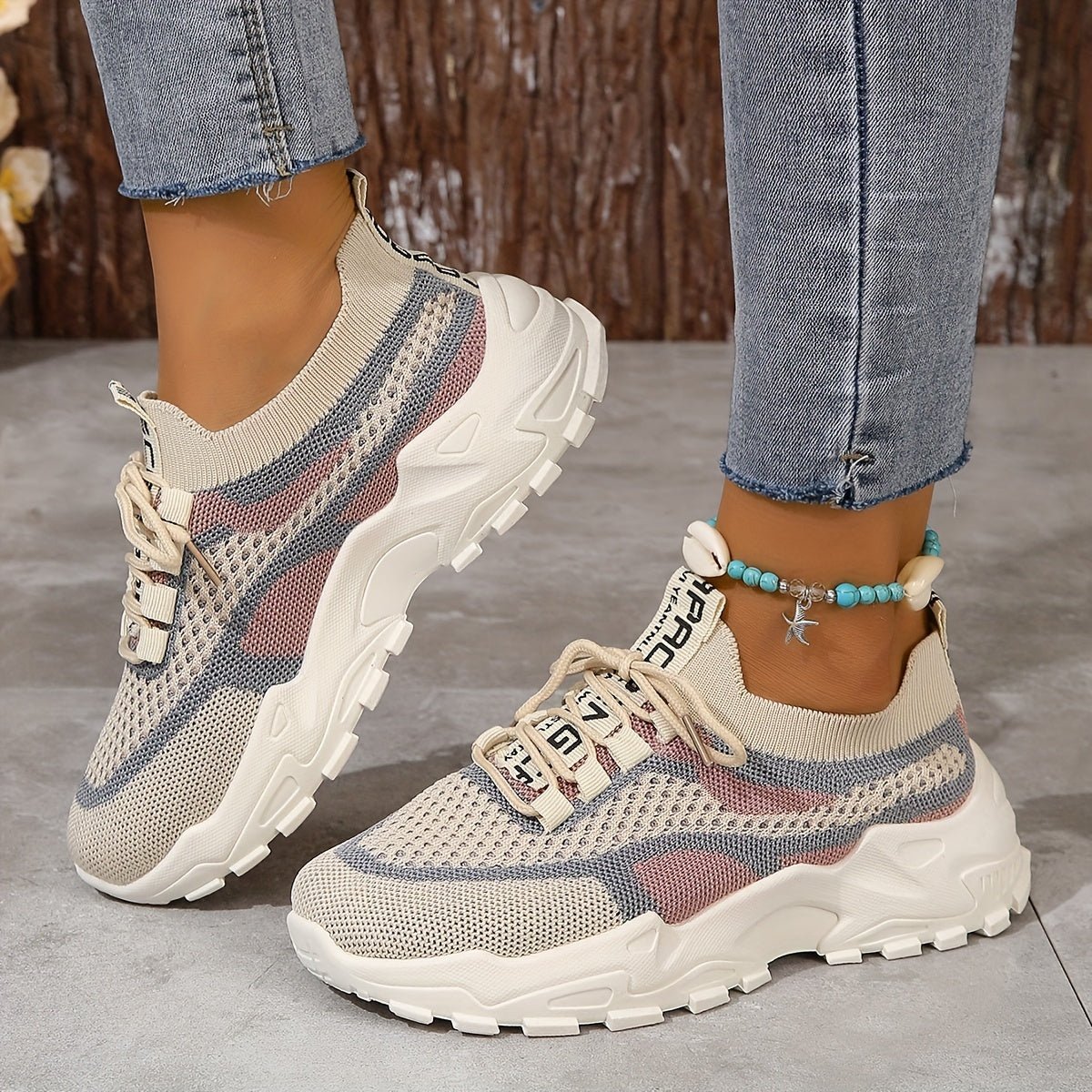 Beige and brown sneakers worn with blue jeans on a concrete floor.