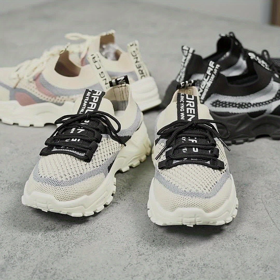 Pair of white sneakers with black laces on a gray surface