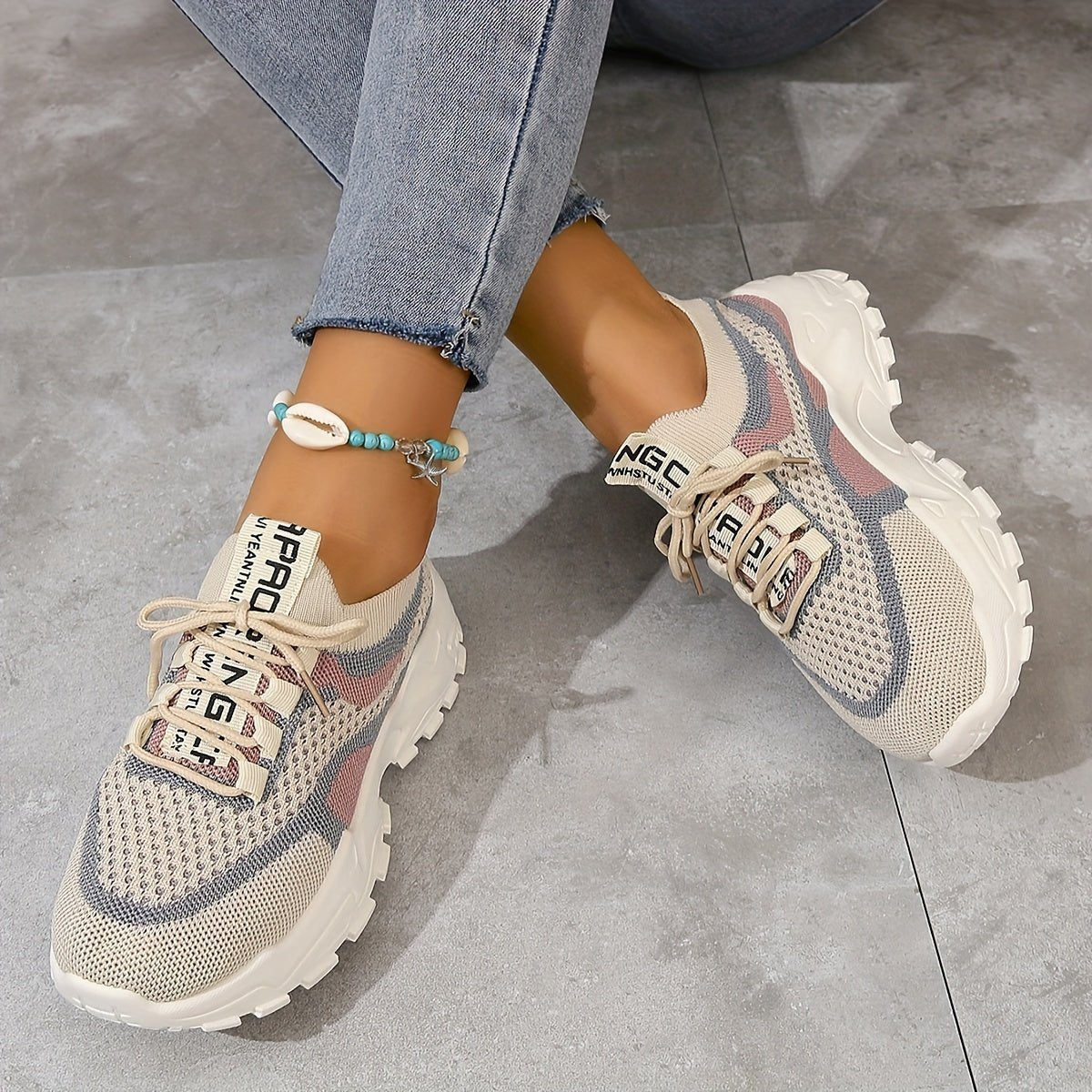 Beige sneakers with text on a gray concrete floor
