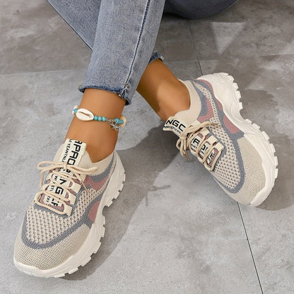 Beige sneakers with text on a gray concrete floor