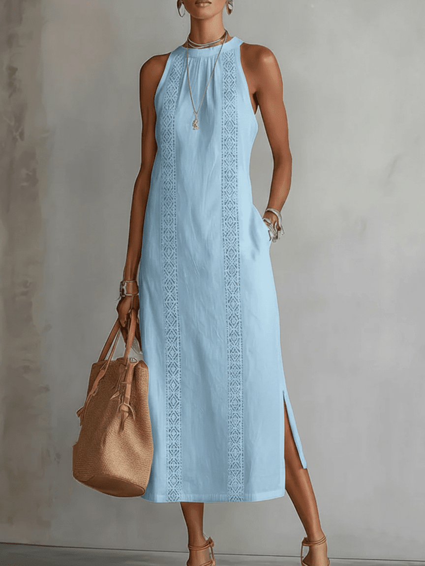 Woman wearing a light blue dress with intricate patterns, holding a brown handbag against a neutral background.