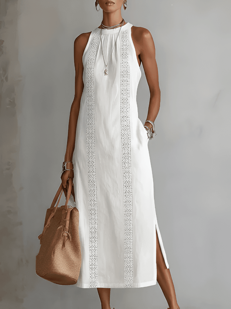 Woman wearing a white dress with lace details and holding a brown bag against a gray background