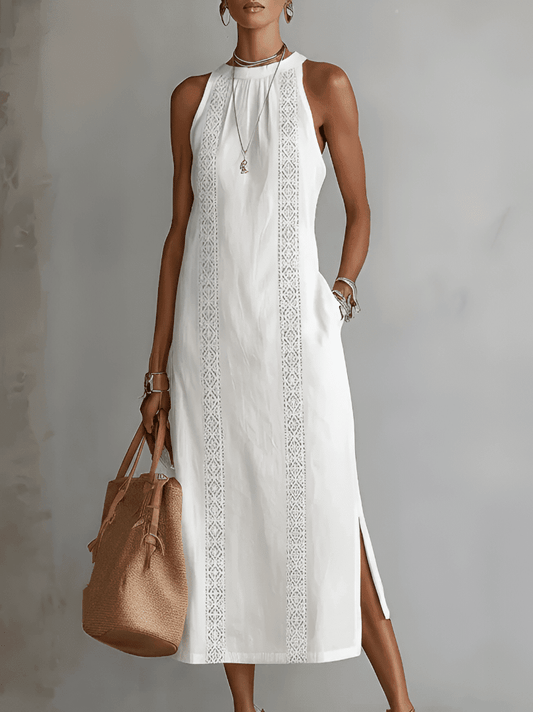 Woman wearing a white dress with lace details and holding a brown bag against a gray background