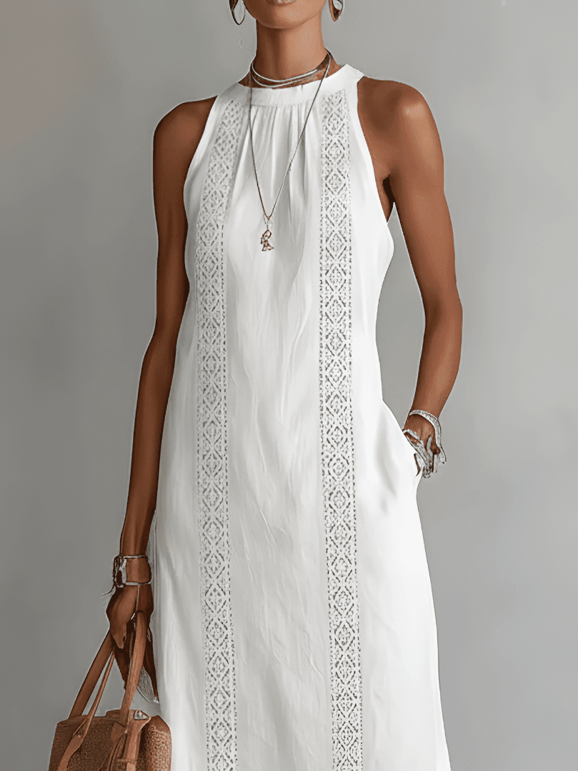 Woman wearing a white sleeveless dress with lace details against a gray background
