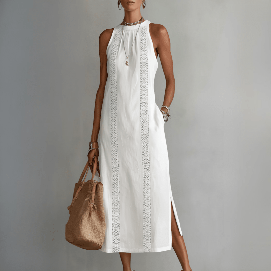 Woman wearing a white dress with lace details and holding a brown bag against a gray background