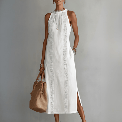 Woman wearing a white dress with lace details and holding a brown bag against a gray background