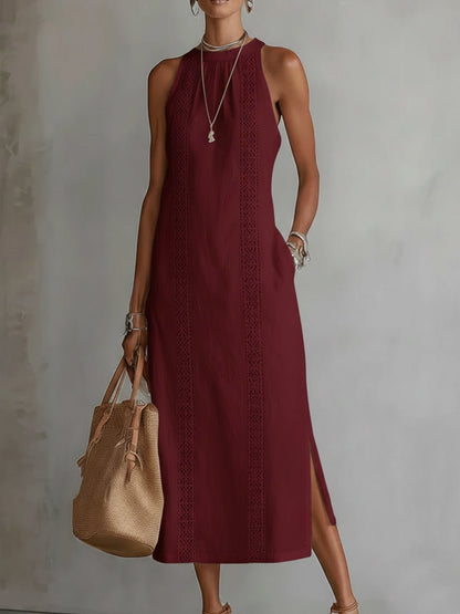 Woman wearing a burgundy dress with a beige handbag against a plain background