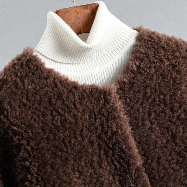 Brown textured sweater with white turtleneck on a hanger against a gray background
