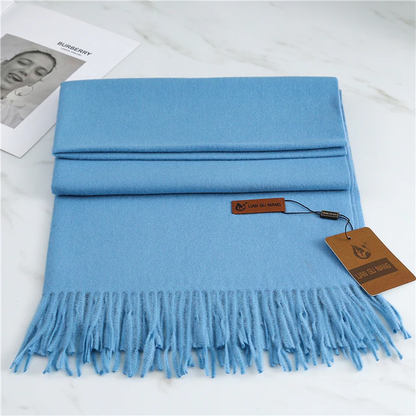 Light blue scarf with fringes and a brand tag on a white surface