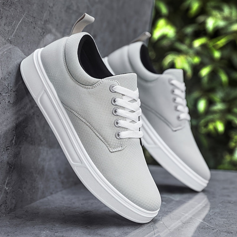 Gray sneakers with white soles leaning against a gray wall with greenery in the background.