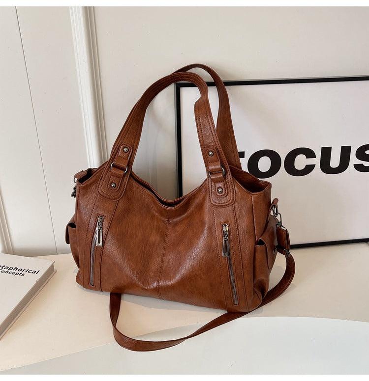 Brown leather handbag on a light surface with a 'FOCUS' sign in the background
