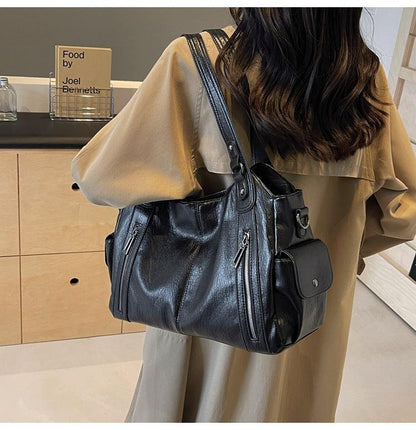 Person wearing a black leather handbag in an indoor setting