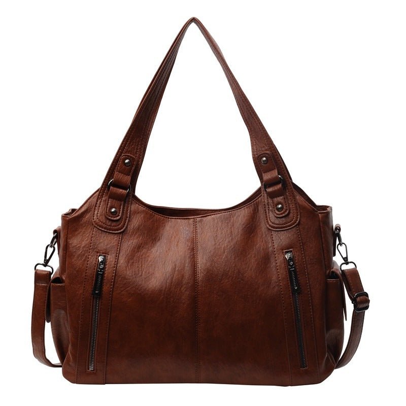 Brown leather handbag with multiple pockets and straps on a white background