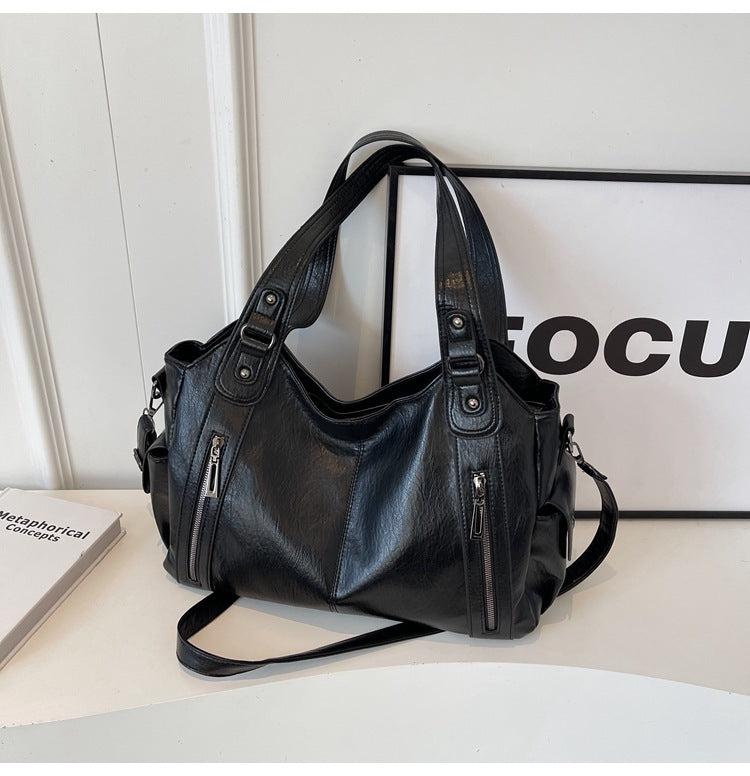 Black handbag on a white surface with a blurred background