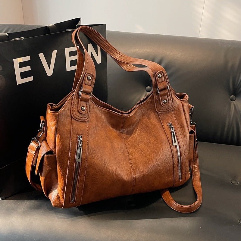 Brown leather handbag on a gray surface with a black background