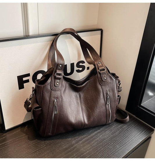 Brown leather handbag on a surface with a 'FOCUS' sign in the background