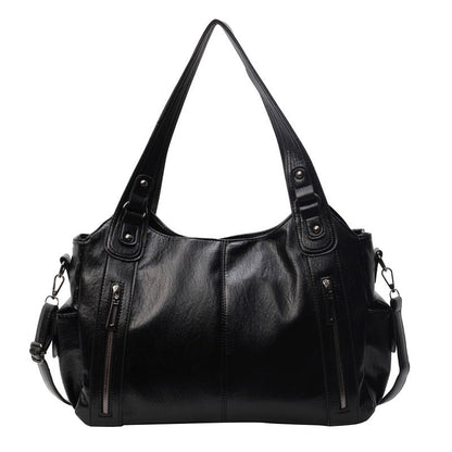 Black leather handbag with multiple pockets and zippers on a white background