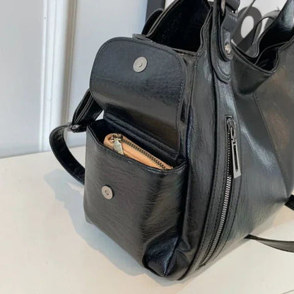 Black leather handbag with a visible pocket on a light surface