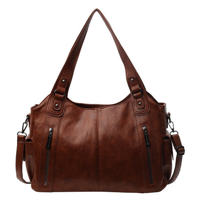 Brown leather handbag with multiple pockets and straps on a white background