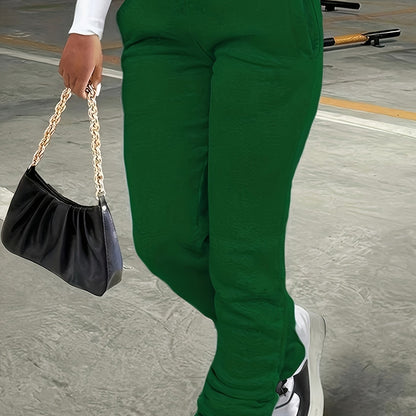 Person wearing green pants holding a black handbag with a gold chain strap.