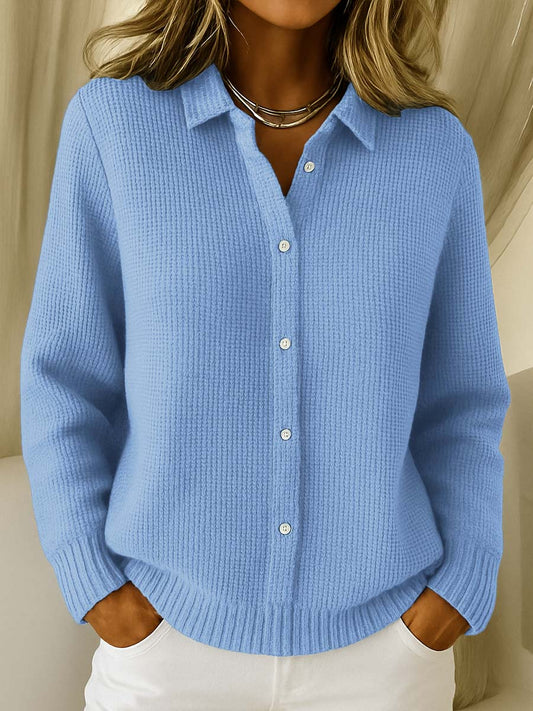 Person wearing a blue knitted cardigan with a neutral background
