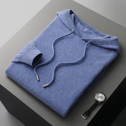 Folded blue hoodie on a gray surface with a watch next to it