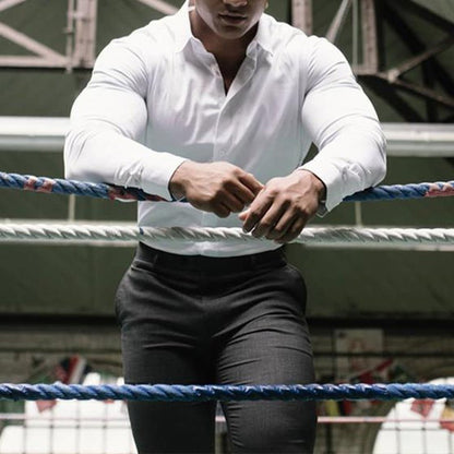 Person in a white shirt and black pants standing in a boxing ring.