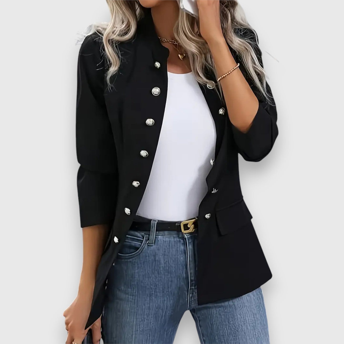 Person wearing a black blazer with silver buttons, white top, and blue jeans on a white background