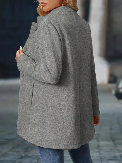 Person wearing a gray coat on a blurred street background