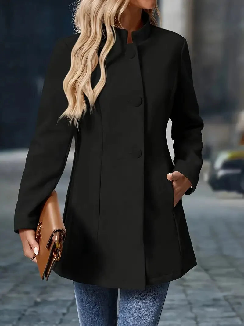 Person wearing a black coat holding a brown clutch on a blurred street background