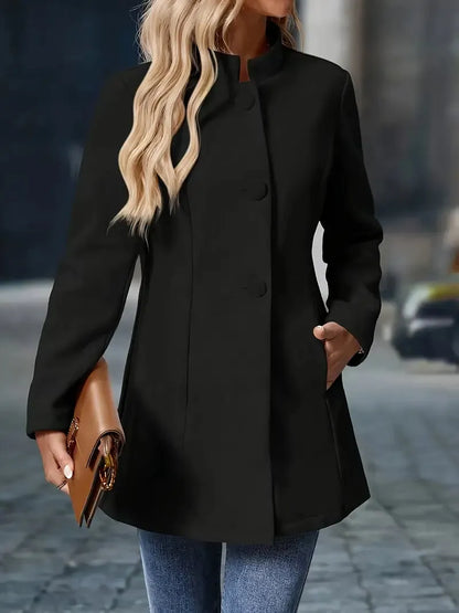 Person wearing a black coat holding a brown clutch on a blurred street background