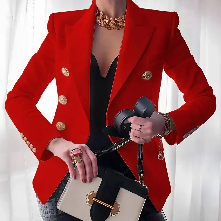 Person wearing a red blazer with gold buttons, holding a black handbag and a phone, on a white background.