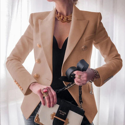 Person wearing a beige blazer with gold buttons, holding a Prada handbag.