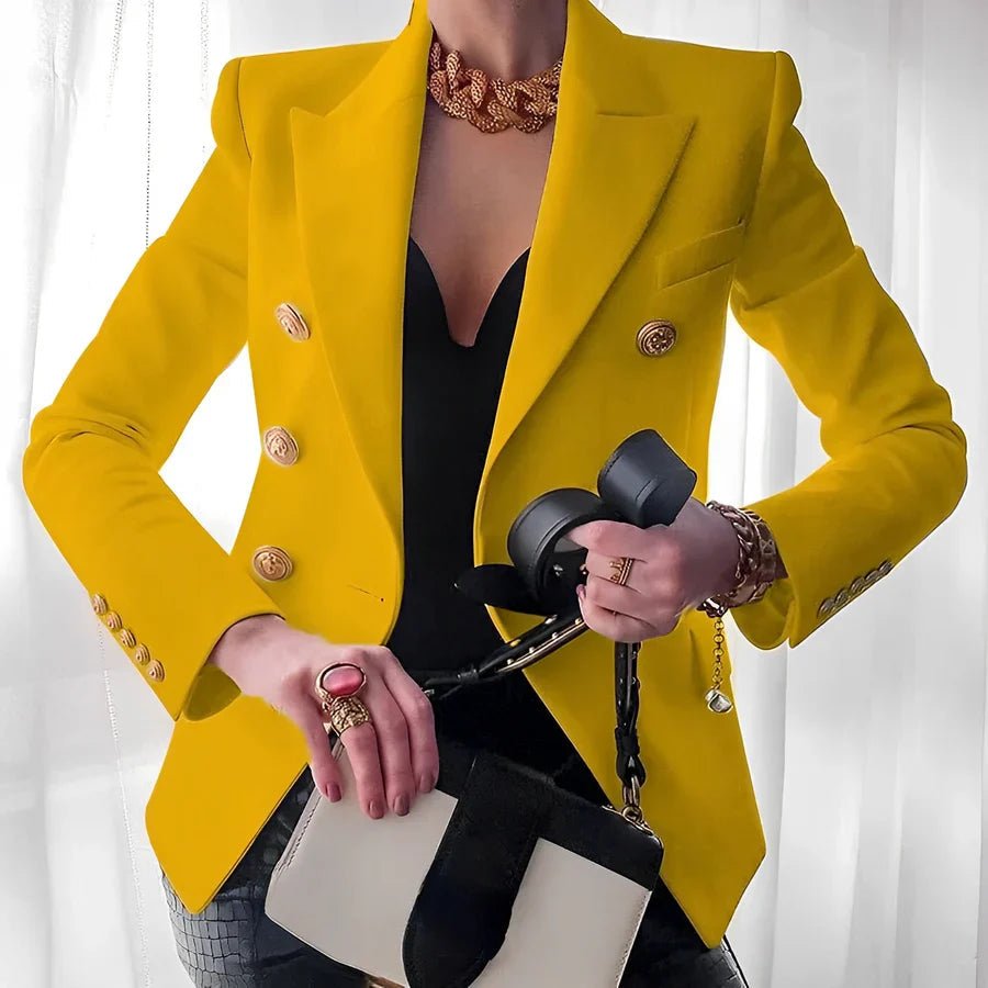 Person wearing a bright yellow blazer with gold buttons, holding a black handbag against a white background.