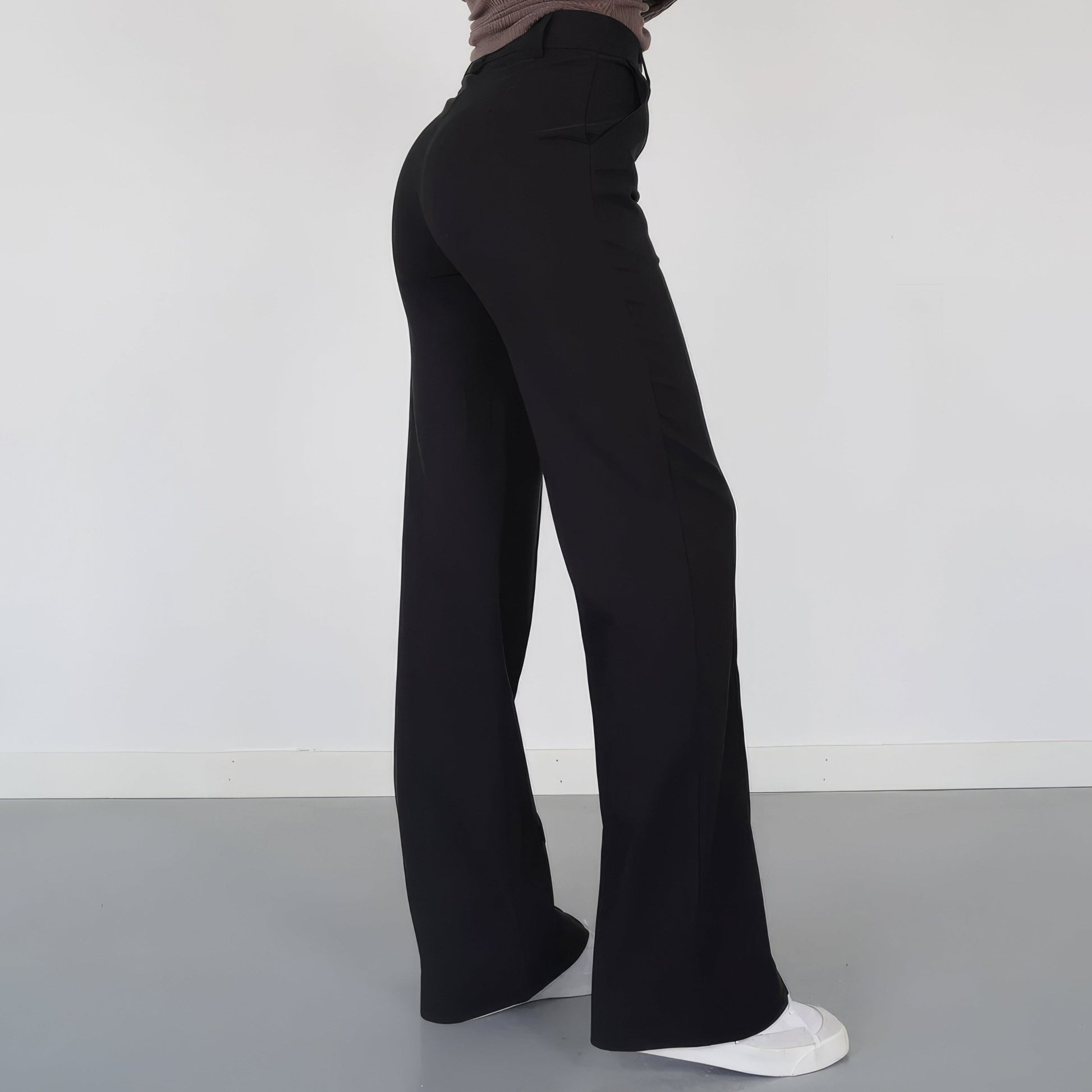 Person wearing black wide-leg pants on a plain background