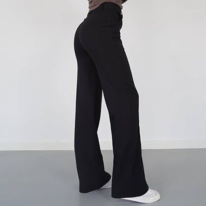 Person wearing black wide-leg pants on a plain background