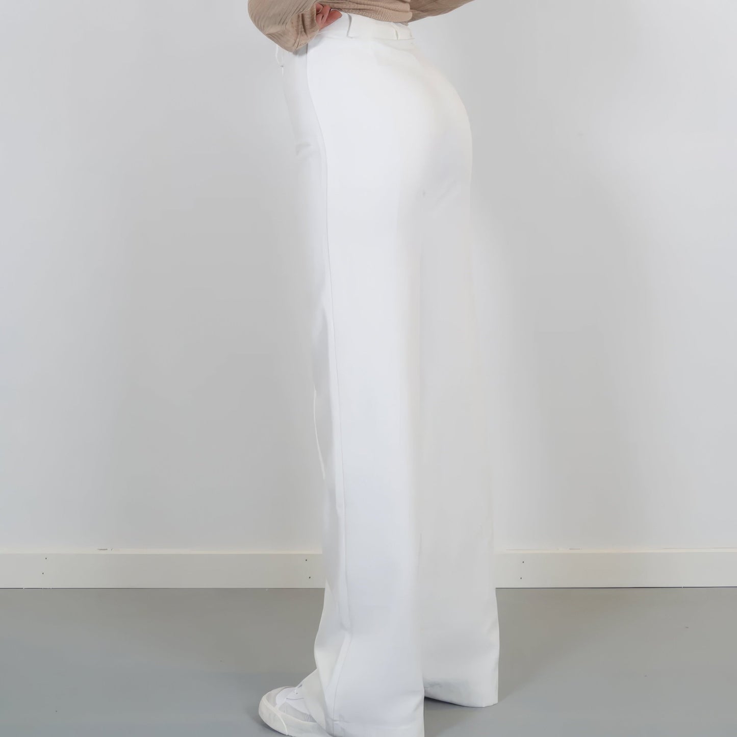 Person wearing white pants against a plain white background