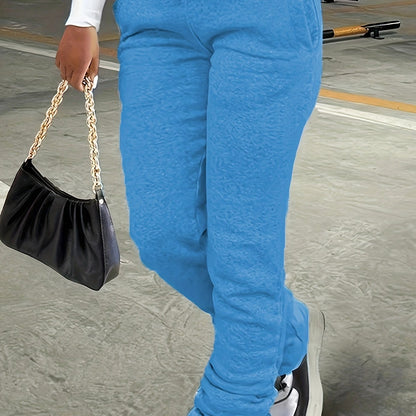 Person wearing blue pants holding a black handbag on a concrete surface