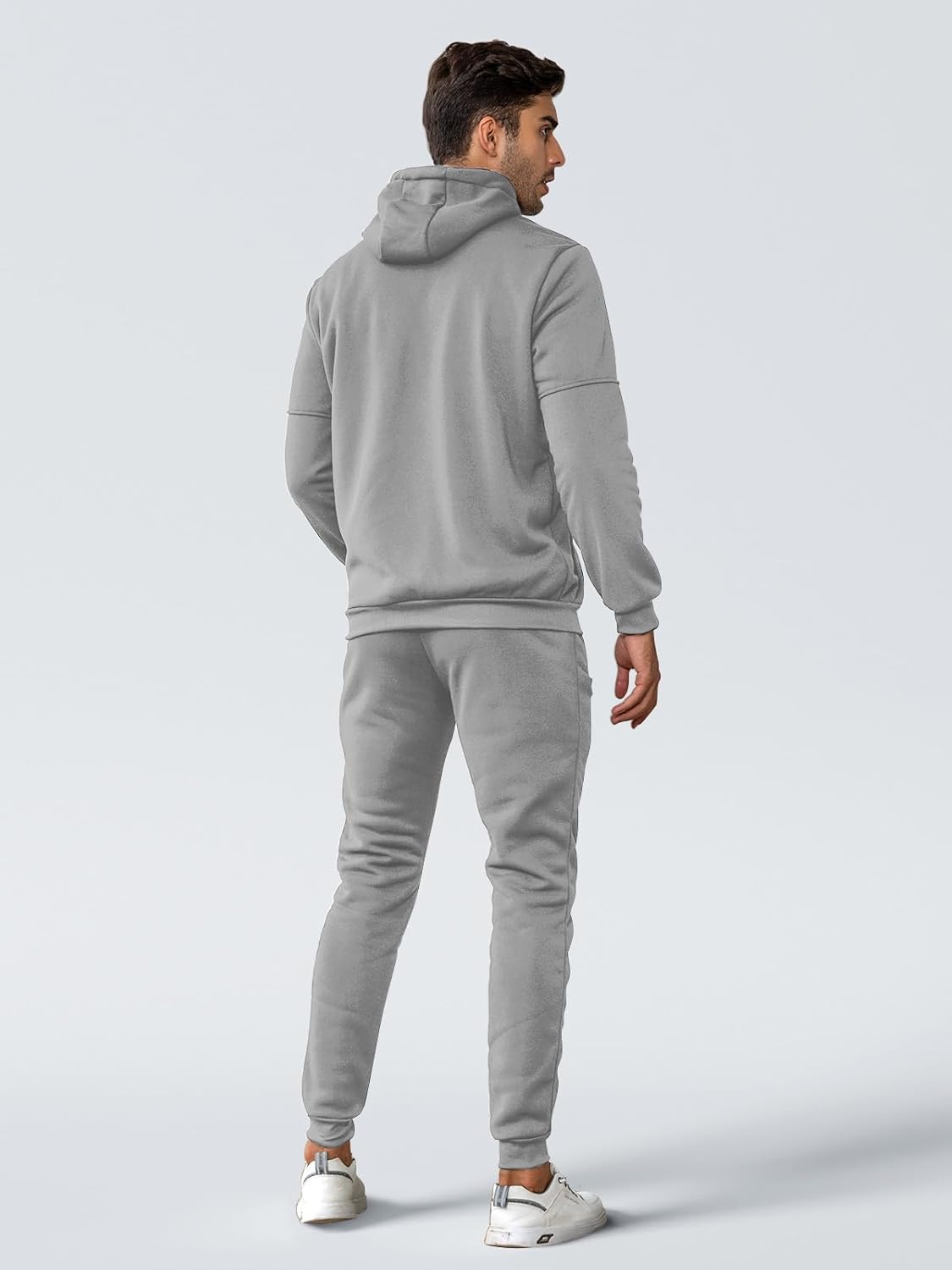 Person wearing a gray tracksuit on a light gray background
