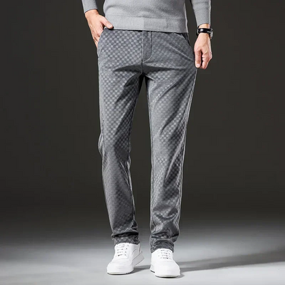 Person wearing gray patterned pants and white shoes on a dark background