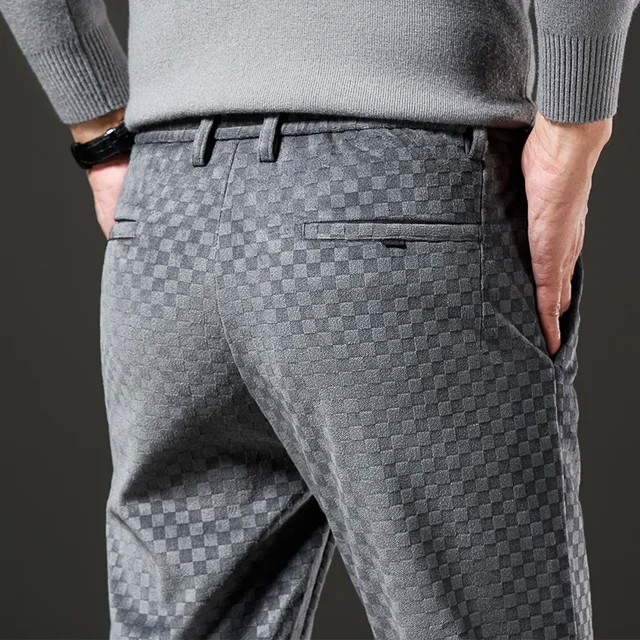 Person wearing gray checkered pants and a gray sweater on a dark background