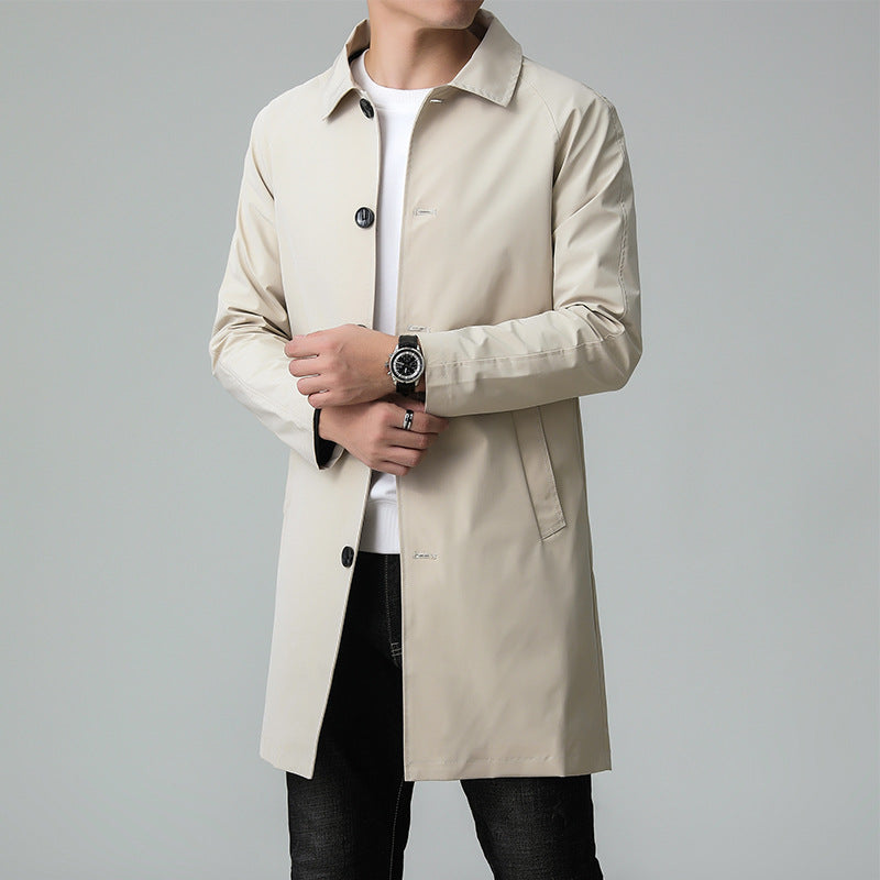 Man wearing a beige trench coat on a gray background